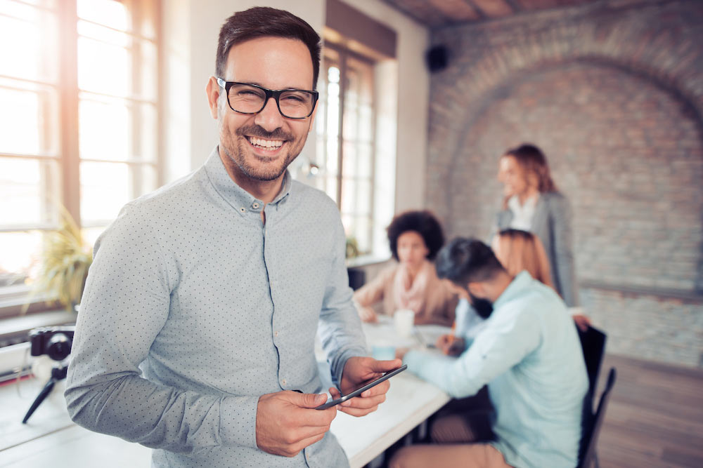 Portrait of smiling young man using tablet in office